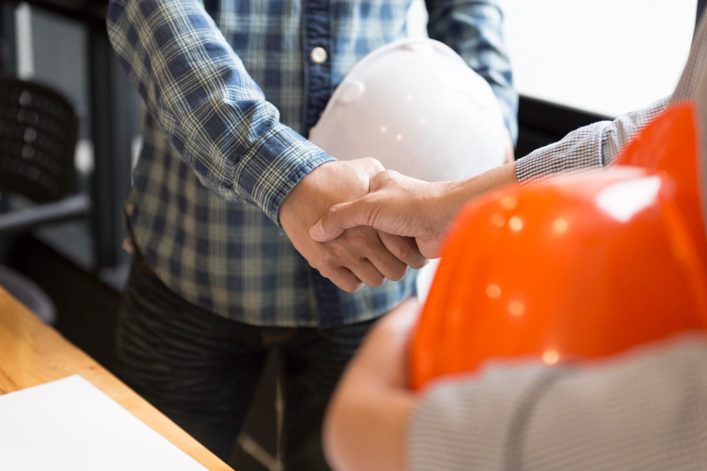 2 hommes sur un chantier sellent leur collaboration pour un marché global de performance en se serrant la main