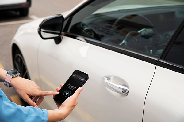 Une femme déverrouille une voiture avec son mobile pour illustrer les services de carsharing ou autopartage.
