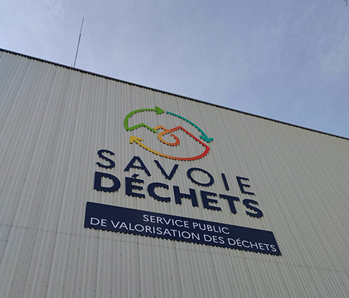 Facade du centre de tri des déchets avec un zoom sur le logo Savoie Déchets