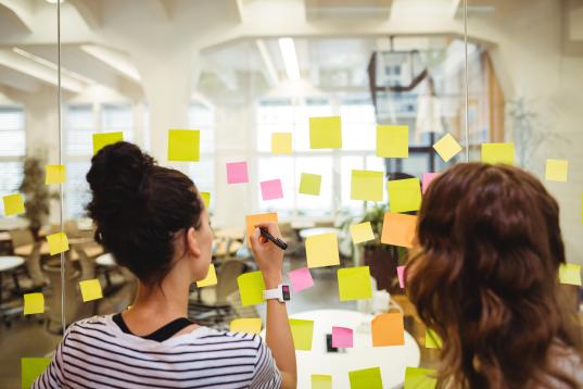 Personnes écrivant sur des post-it pour illustrer la démarche participative appliquée à la conception du bâtiment administratif.
